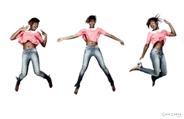 femme noire en jean et haut rose en train de sauter